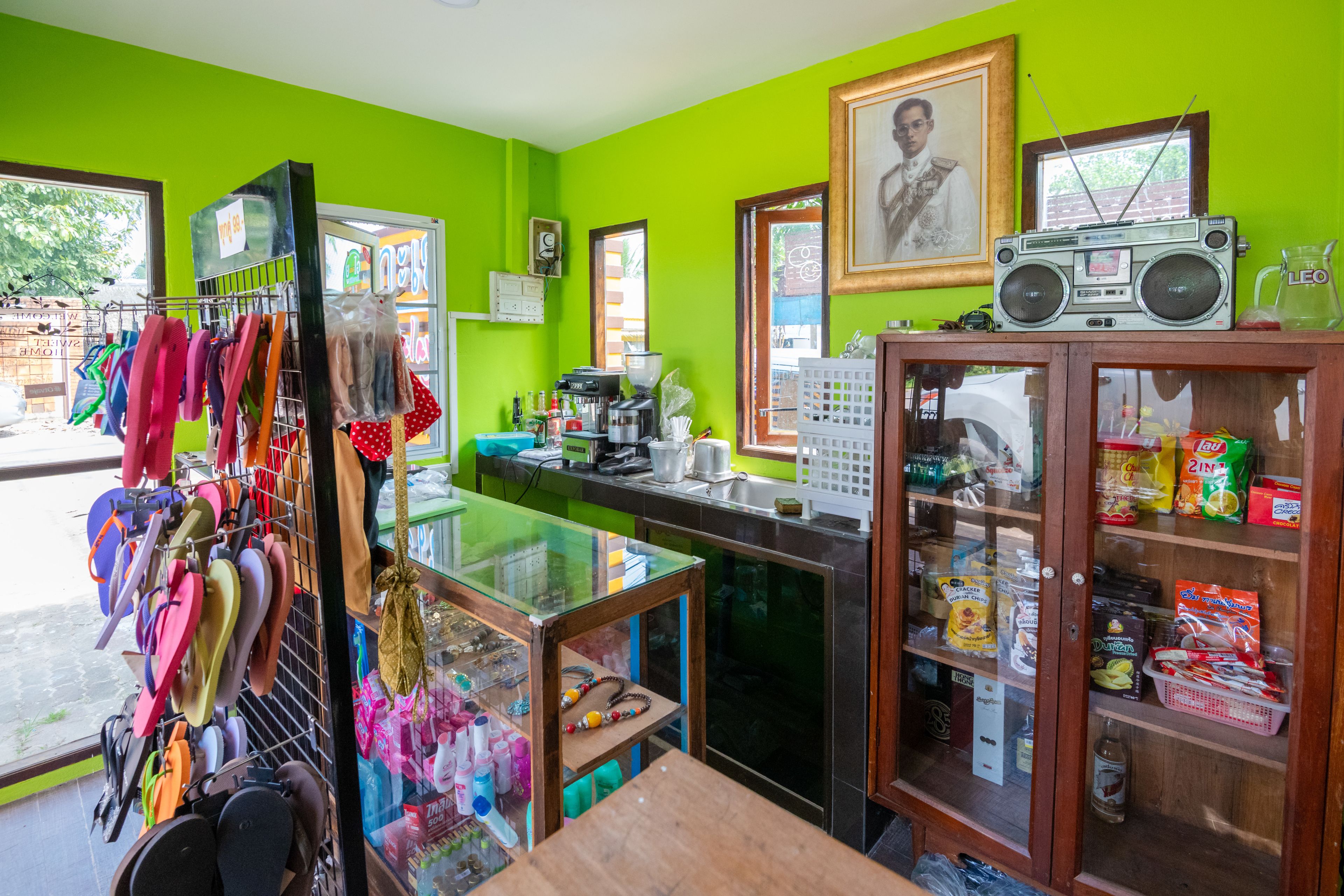 A brightly colored room with a glass display case filled with snacks, a radio on top of a cabinet, and flip-flops hanging on a rack.