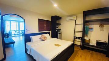 Una camera d'albergo con un letto, una scrivania, una sedia, un condizionatore e vista sull'esterno.