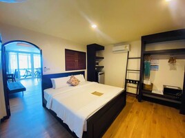Una camera d'albergo con un letto, una scrivania, una sedia, un condizionatore e vista sull'esterno.