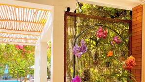 Uma área externa coberta com piscina, um banco de madeira e um jardim decorativo com flores.