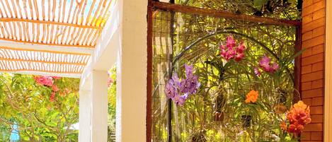 A covered outdoor area with a pool, a wooden bench, and a decorative plant enclosure with flowers.