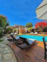 Una piscina al aire libre, sillones reclinables de piscina