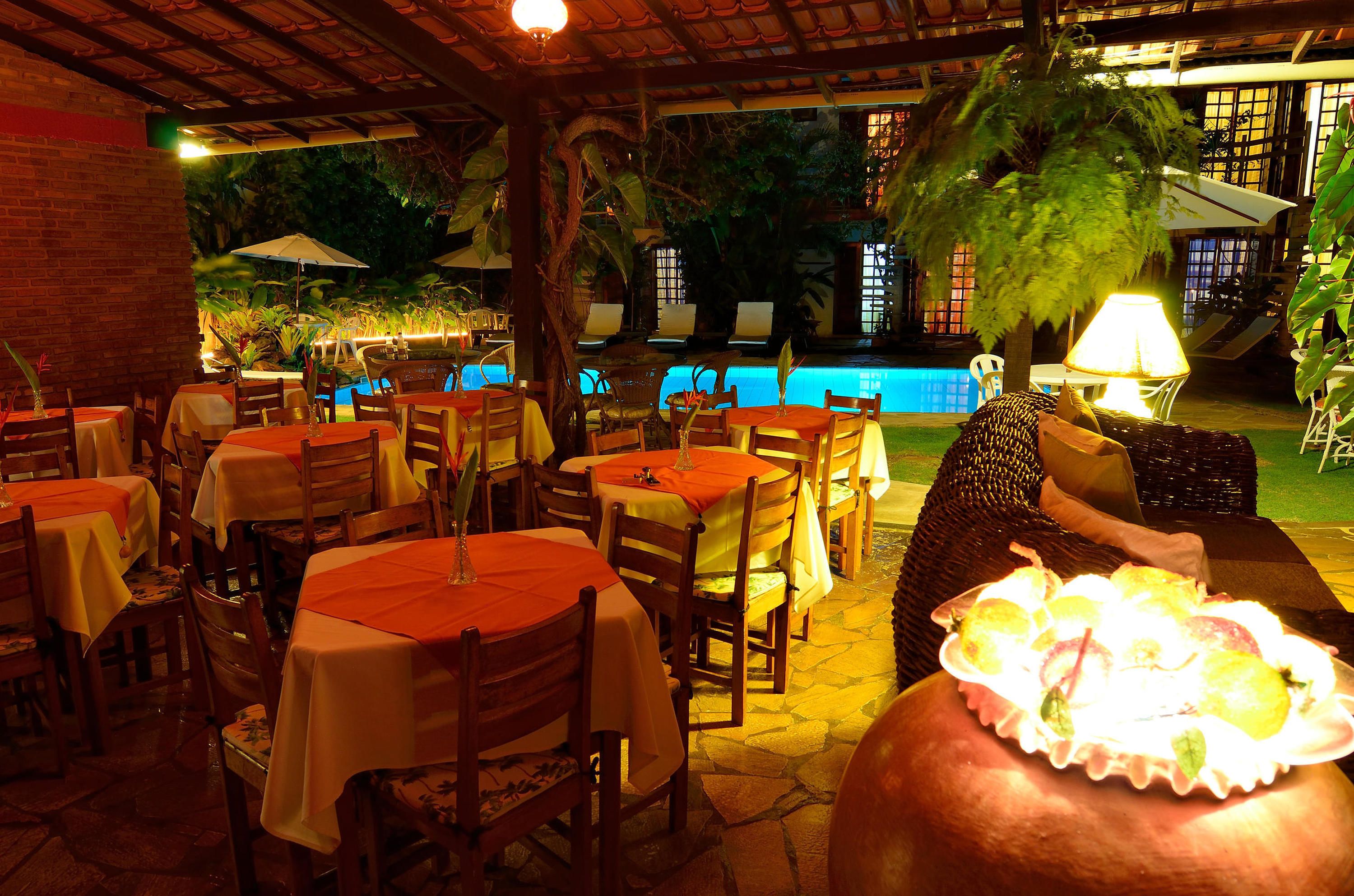 An outdoor dining area with tables and chairs, a pool, and a lamp.