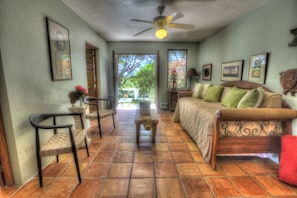 A spacious living room with a sofa, chairs, and a ceiling fan.