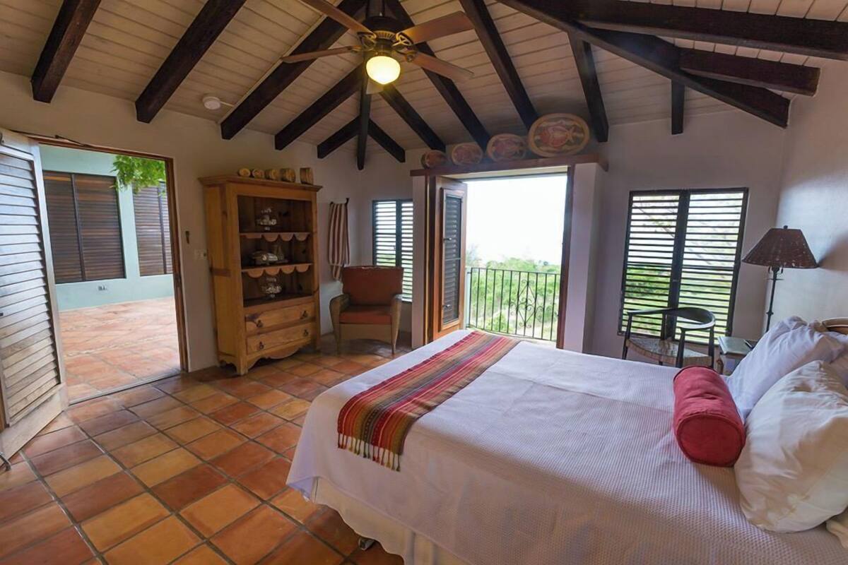 Une chambre à coucher avec un lit, une armoire en bois, une chaise et un balcon.