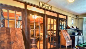 A library with wooden doors, a billiards table, and a coffee machine. - Hacienda Tamarindo (Vieques)