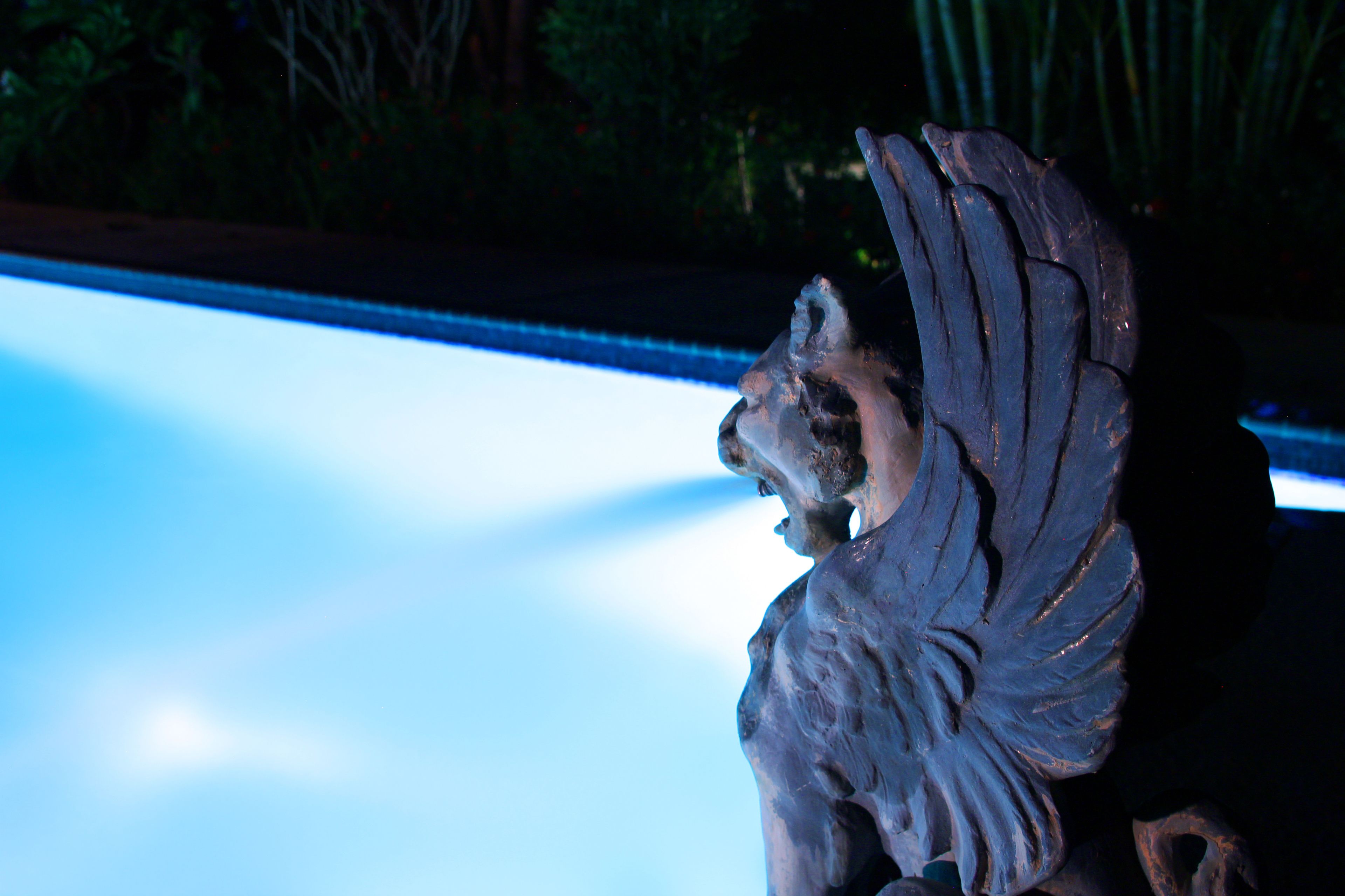 A sculpture of a winged figure, possibly an angel, with a blurred background.