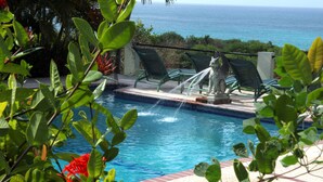 A pool with a statue, surrounded by greenery and overlooking the ocean. - Hacienda Tamarindo (Vieques)