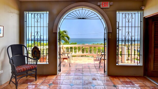 A room with a view of the ocean, a chair, and an exit sign. - Hacienda Tamarindo (Vieques)