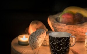 A candle, a mug, and a bowl of fruit on a wooden table. - Appartments Am Bach (Gerlos)