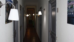 A hallway with doors on both sides, each with a light fixture above.