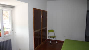 A room with a sliding door closet, a radiator, a green chair, and a bed with a green bedspread.