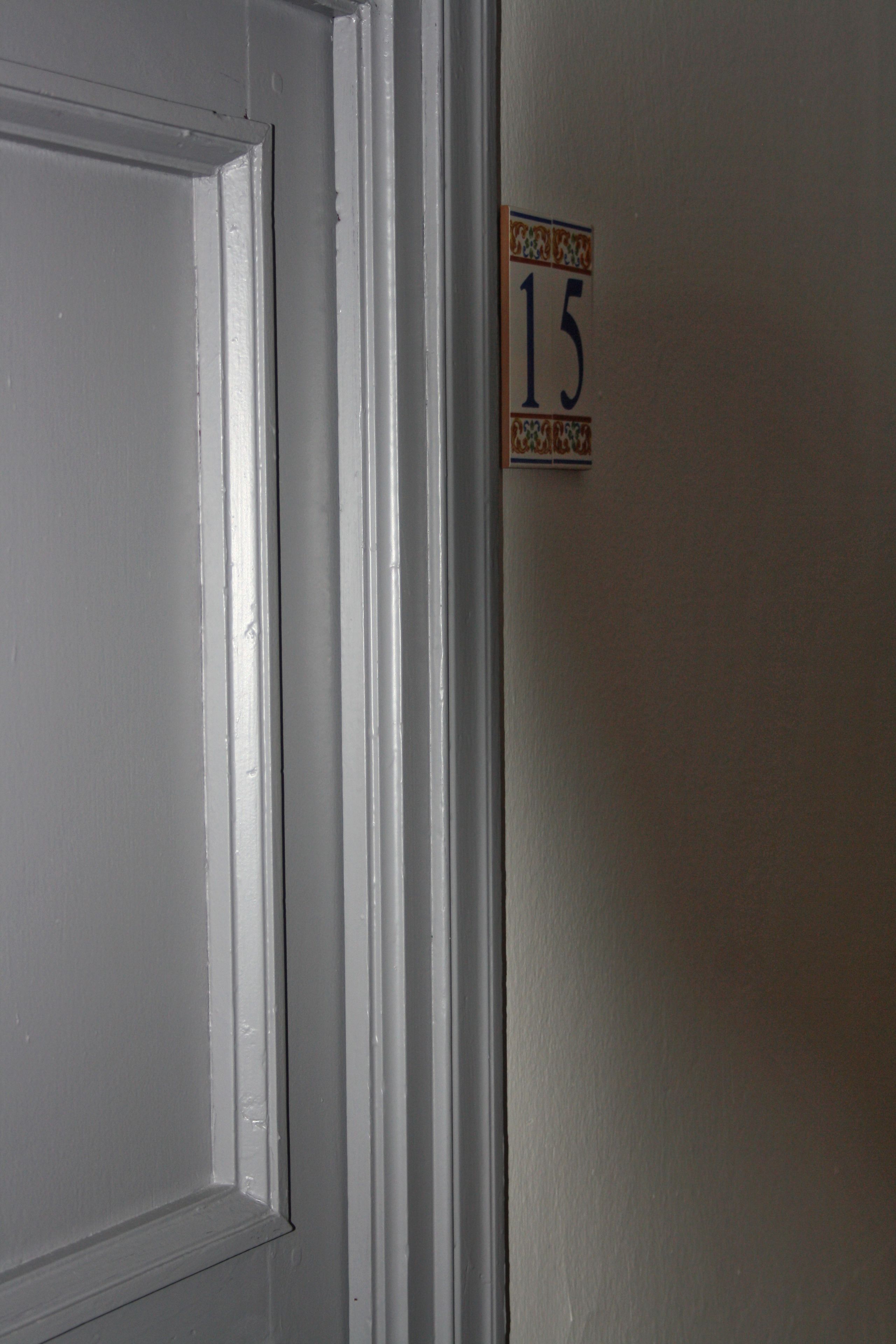 A white door with a small sign on the adjacent wall indicating room number 15.