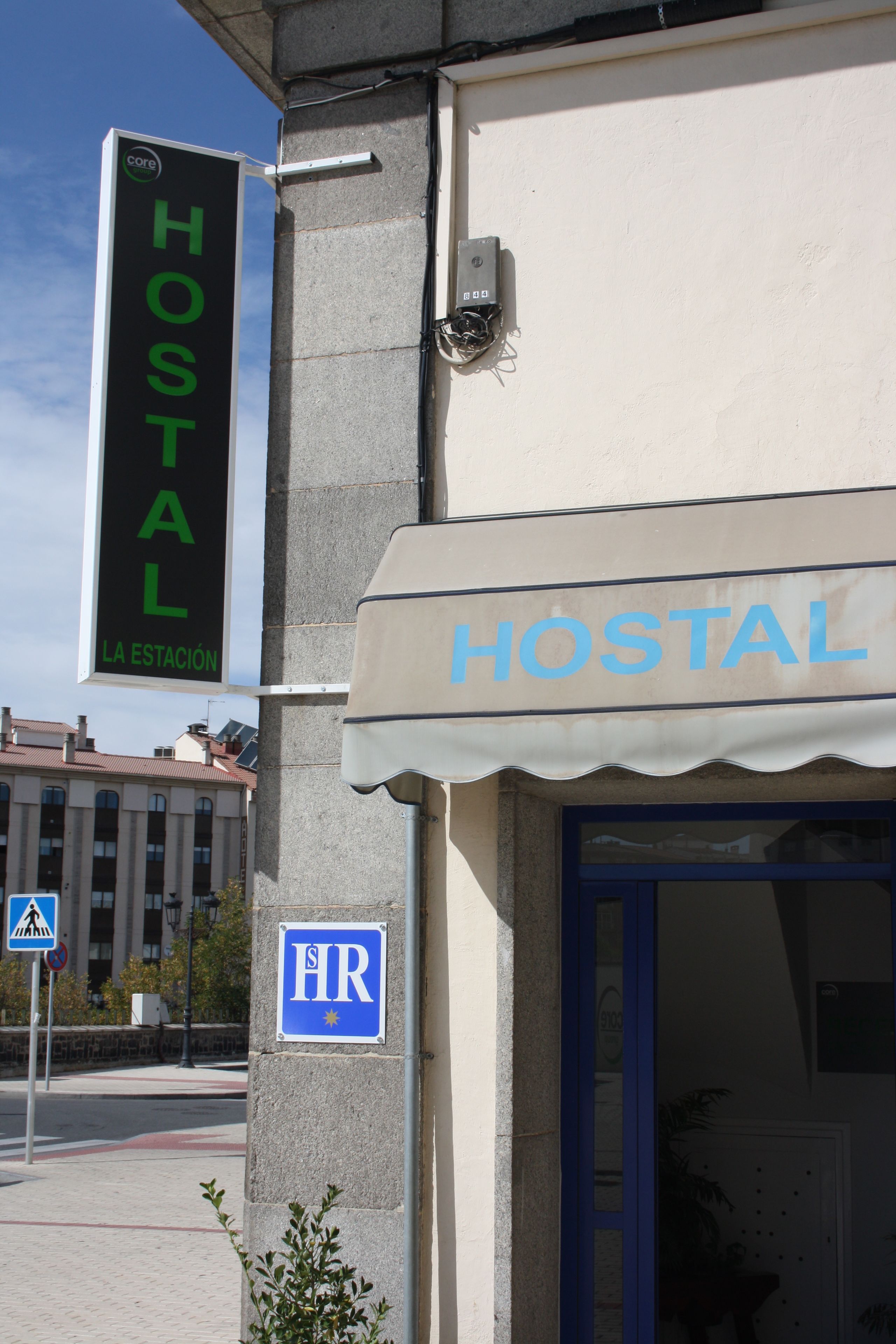 Un hostal con un letrero que dice "HOSTAL" y una señal azul con las letras "HR" en la pared.