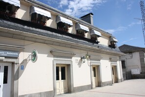 Un edificio con un letrero que indica un restaurante, un anuncio de cerveza y un letrero de estacionamiento.