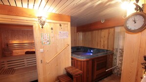 A wooden sauna room with benches, a hot tub, and a wooden door with a sign. - Les Chalets du Villard (Saint-Veran)