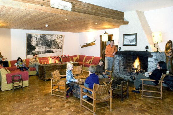 A cozy lounge area with wooden furniture, a fireplace, and a large painting on the wall.