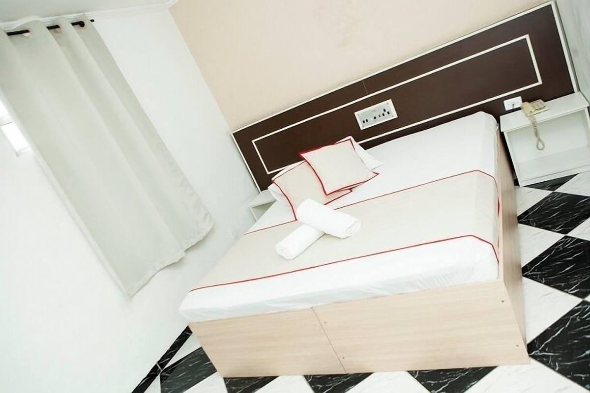 A neatly made bed with a wooden headboard, a white pillow, and a rolled white towel.