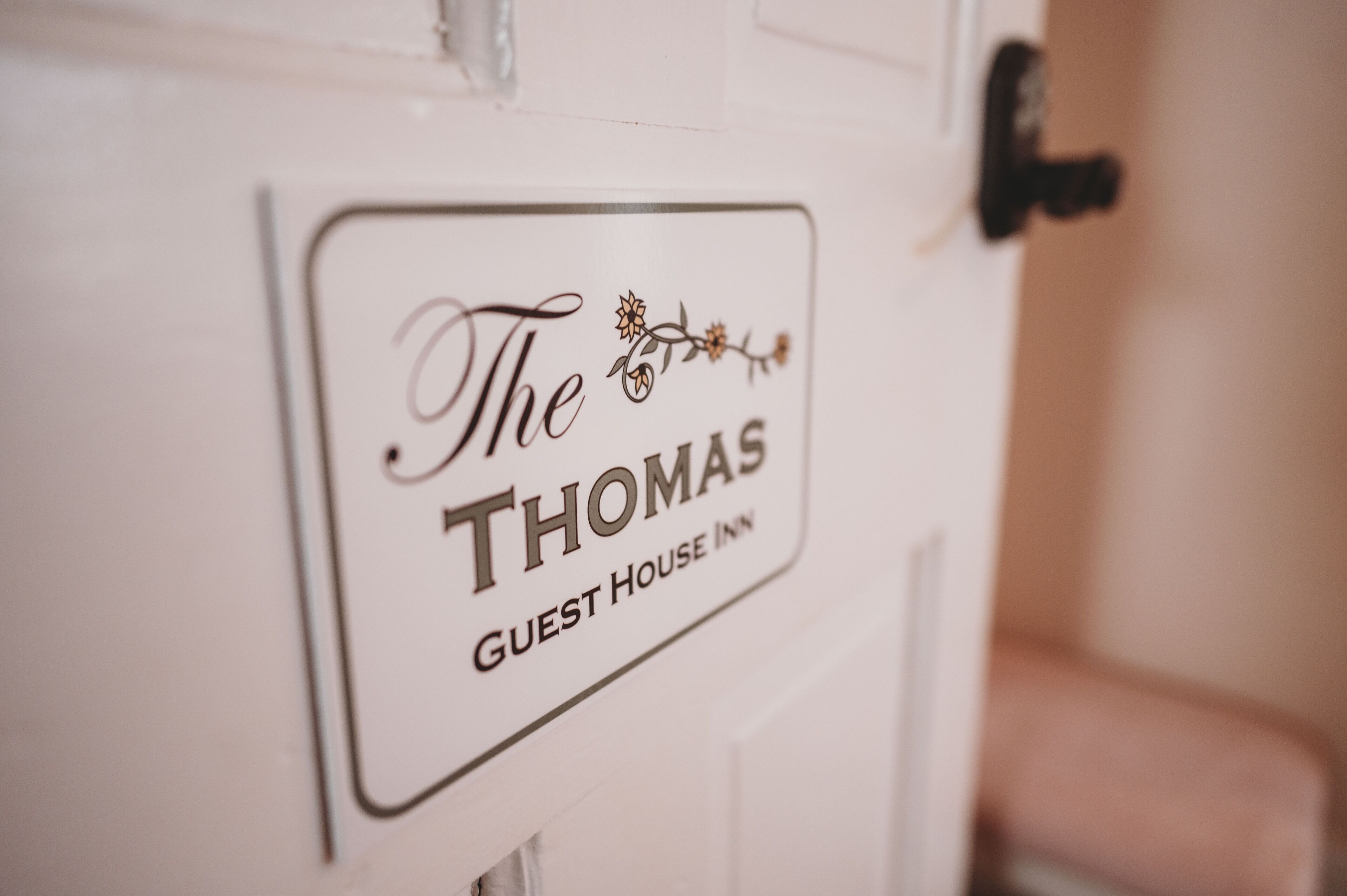 A sign on a door that reads "The Thomas Guest House Inn."