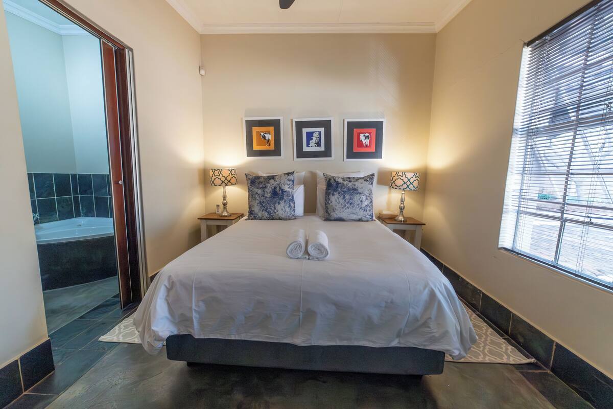A hotel room with a large bed, two bedside tables with lamps, and three framed pictures on the wall.