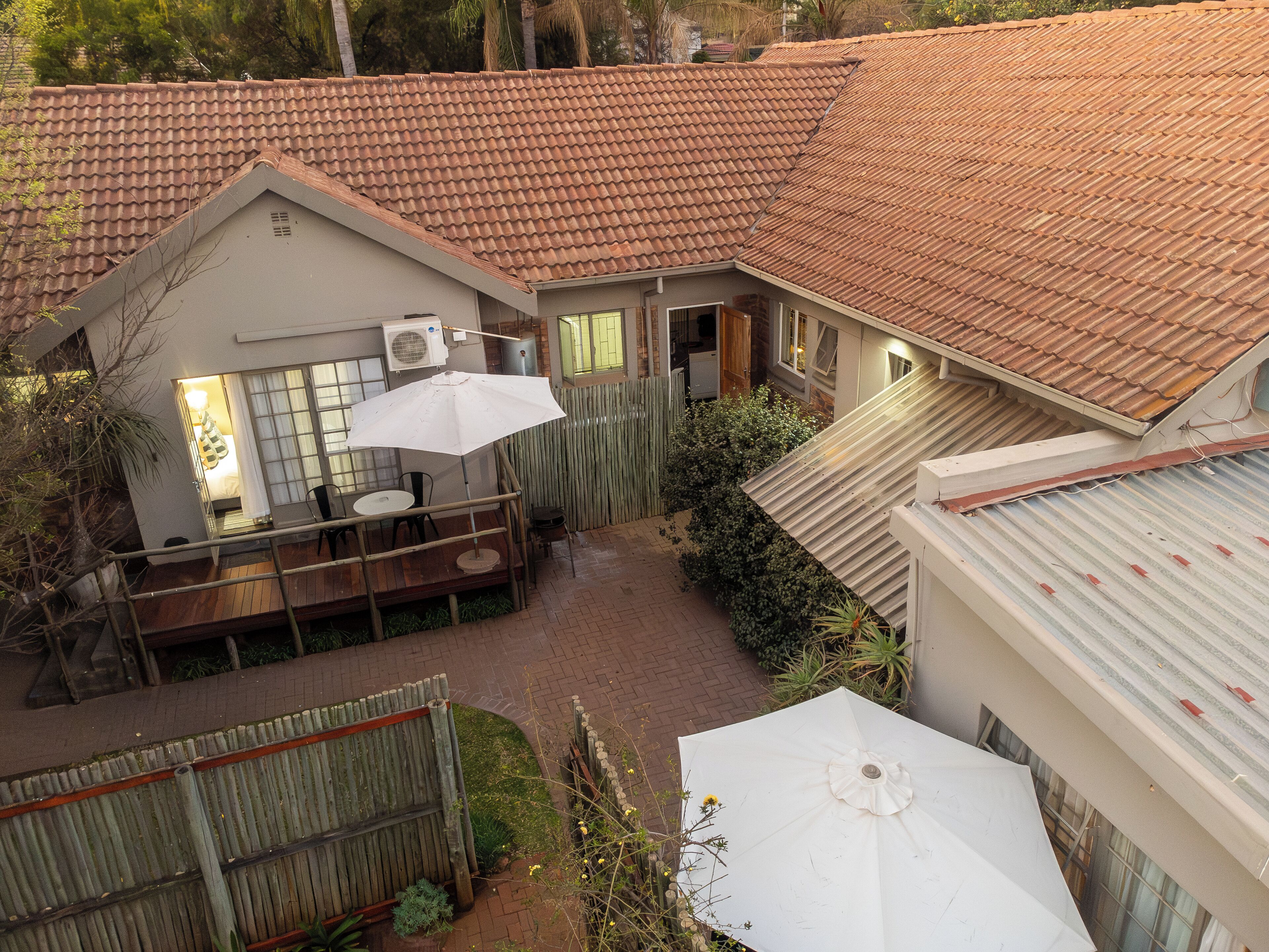 A courtyard with a covered seating area, a small building with a tiled roof, and a large umbrella.