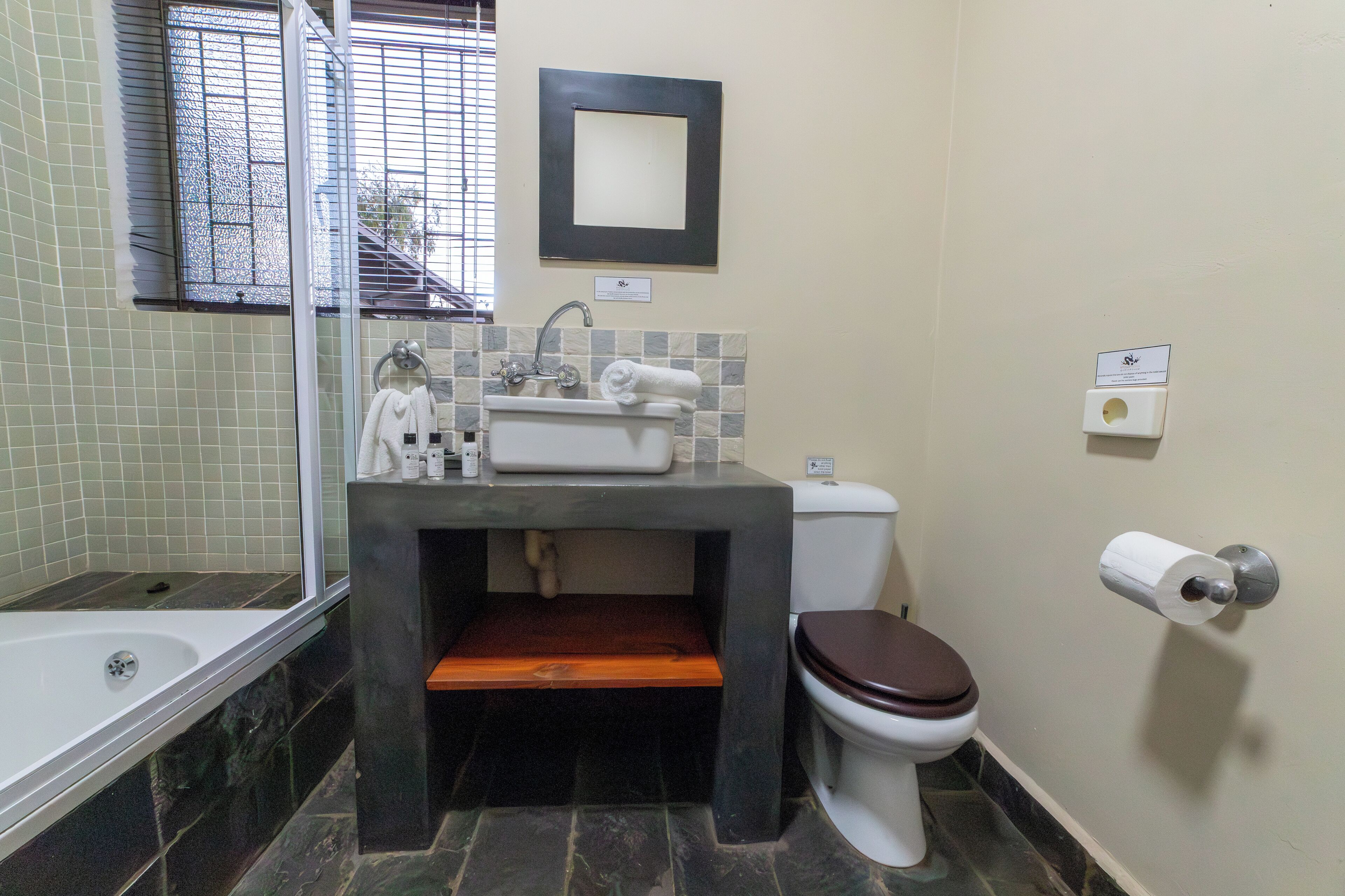 Une salle de bain comprenant une baignoire, un lavabo avec un miroir au-dessus, des toilettes et un porte-serviettes.