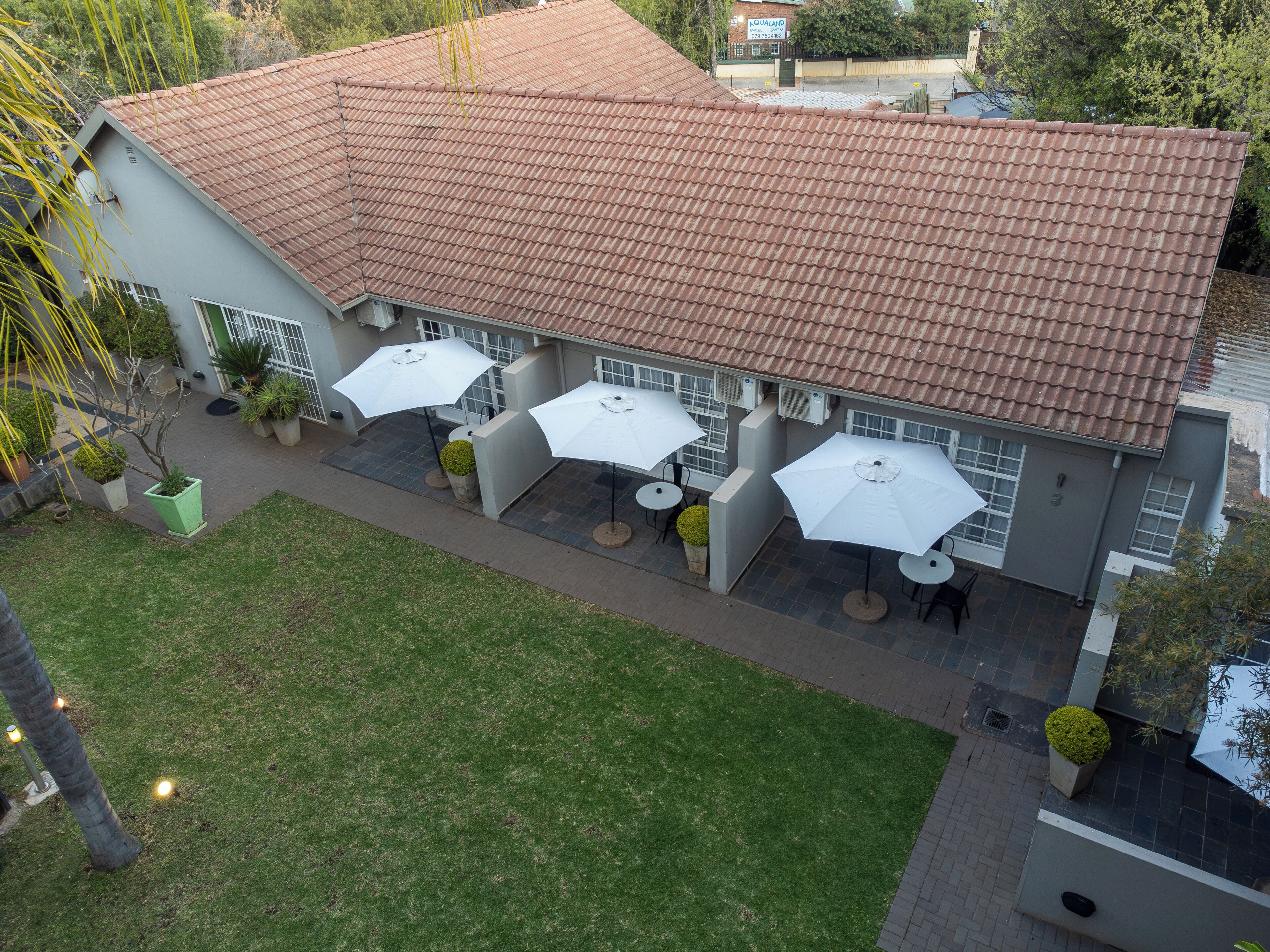 A building with a tiled roof, outdoor seating with umbrellas, and a well-maintained lawn.