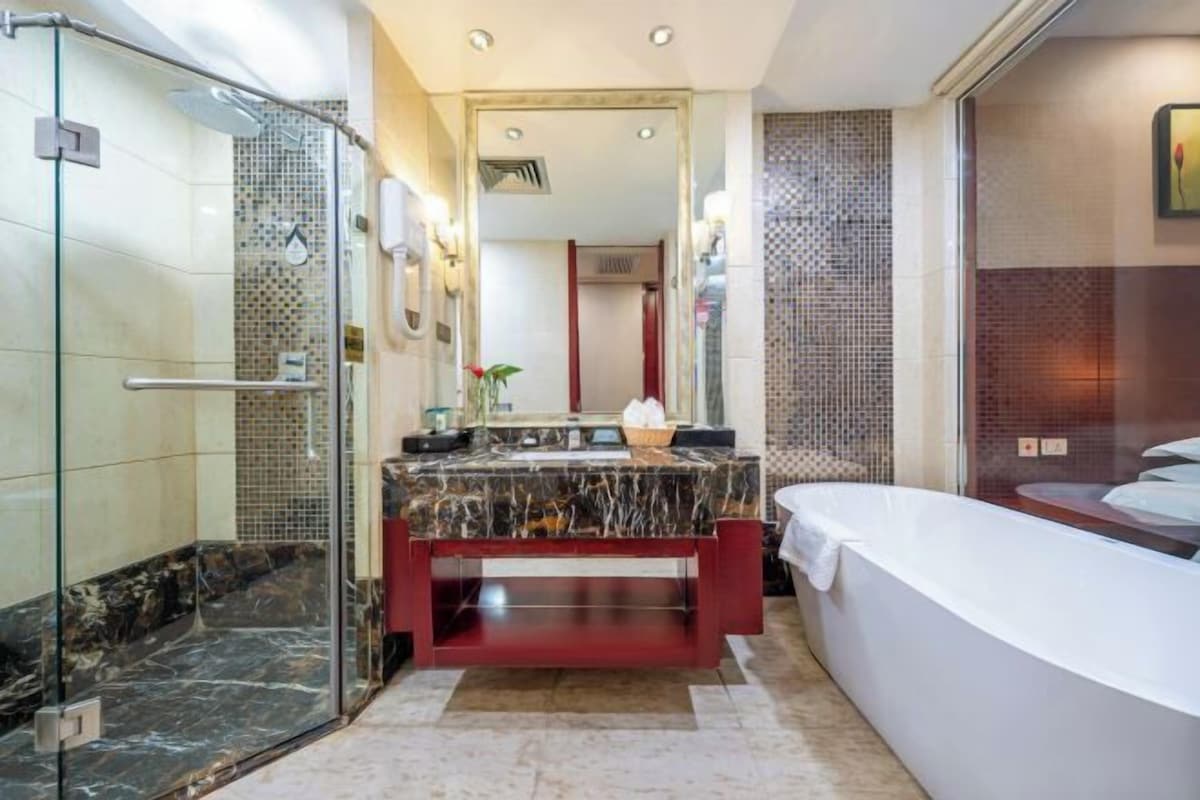 Een moderne badkamer met een douchecabine van glas, een marmeren wastafel en een vrijstaand bad.