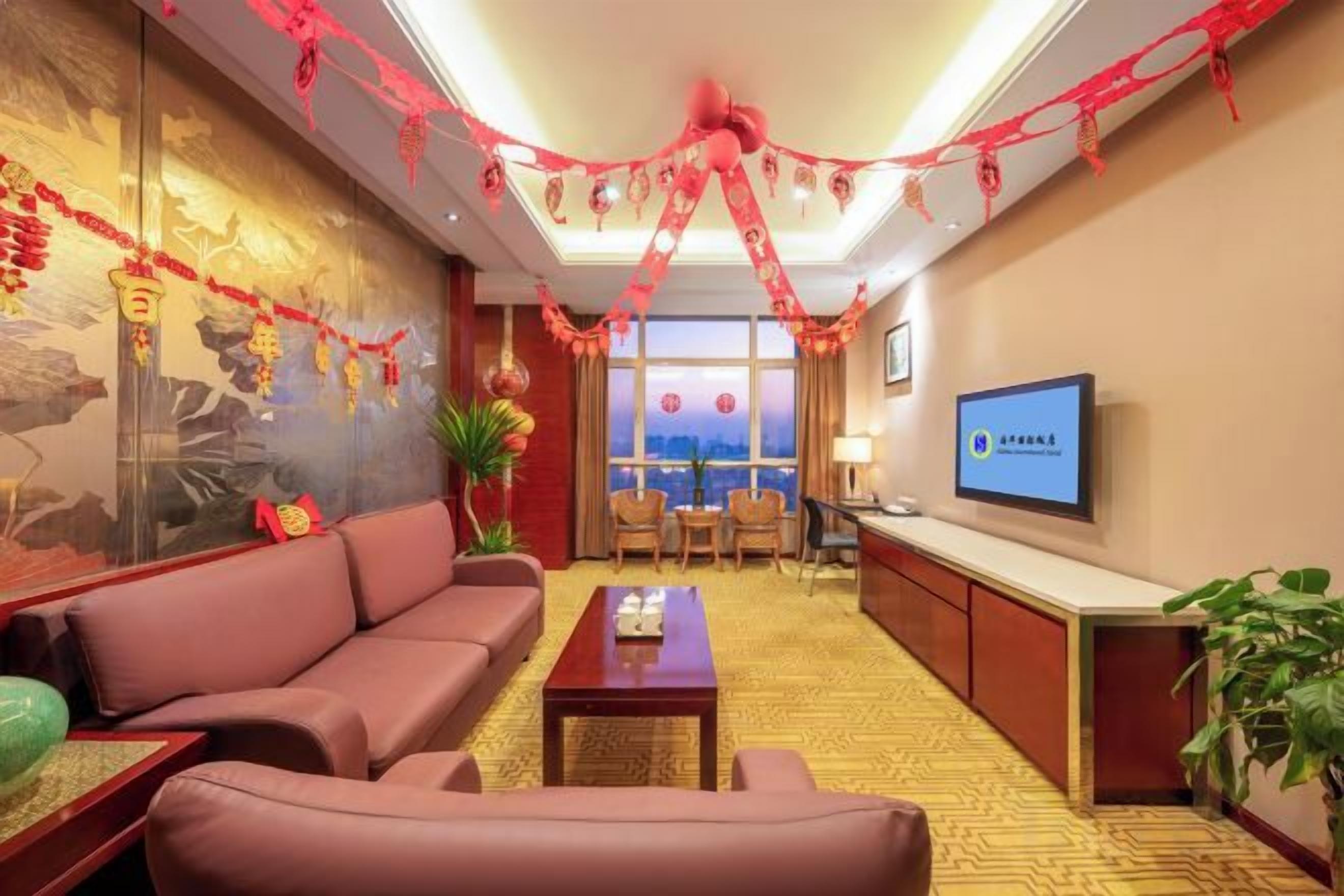 A hotel lobby with a sofa, a coffee table, a television, and a decorative wall.