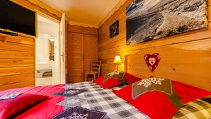 Ein Zimmer mit Holzboden, einem Bett, einem Stuhl, einem Bild und einer herzförmigen Dekoration an der Wand.