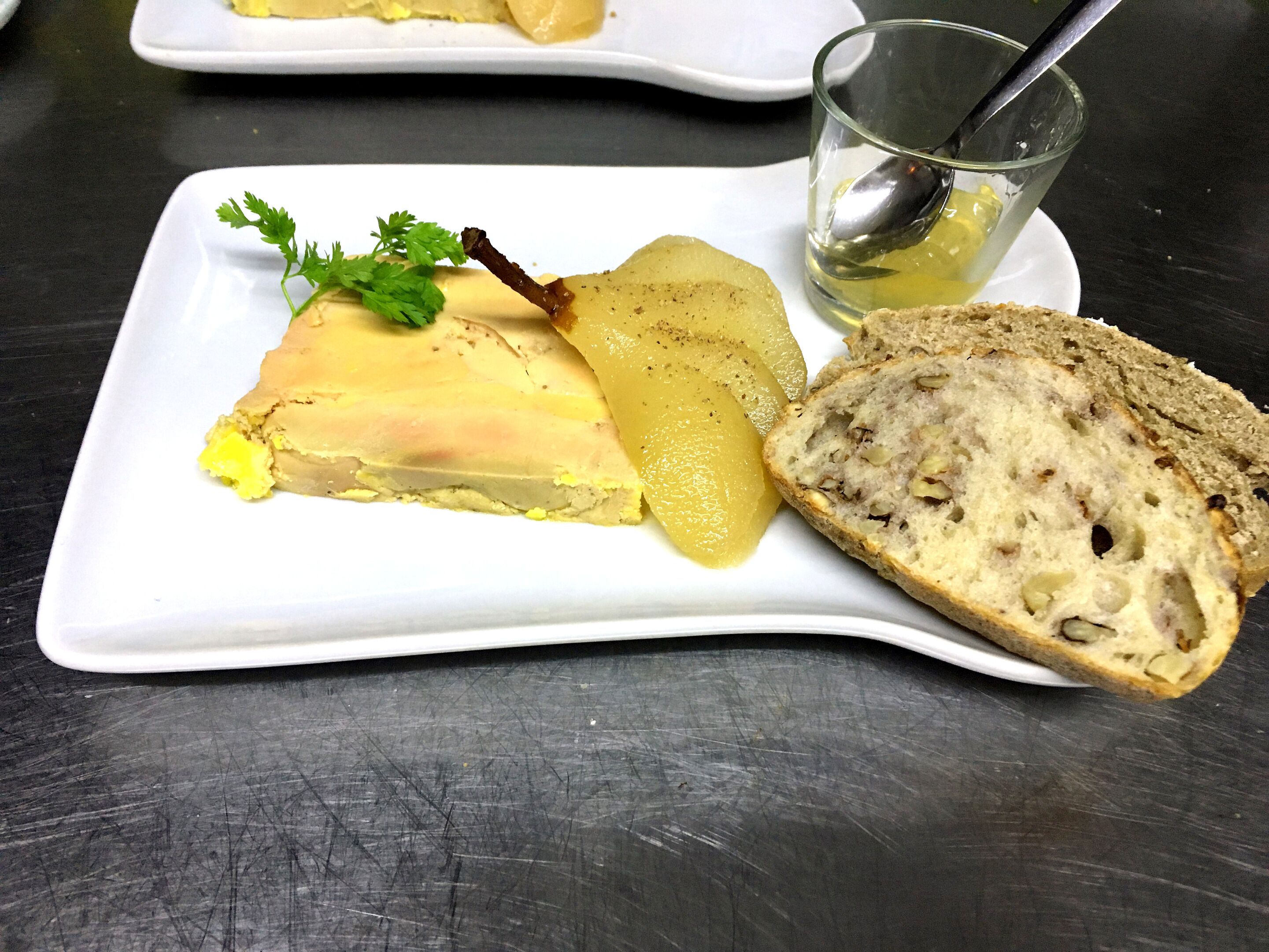 Une assiette blanche sur laquelle on voit une tranche de fromage, une poire et un morceau de pain.