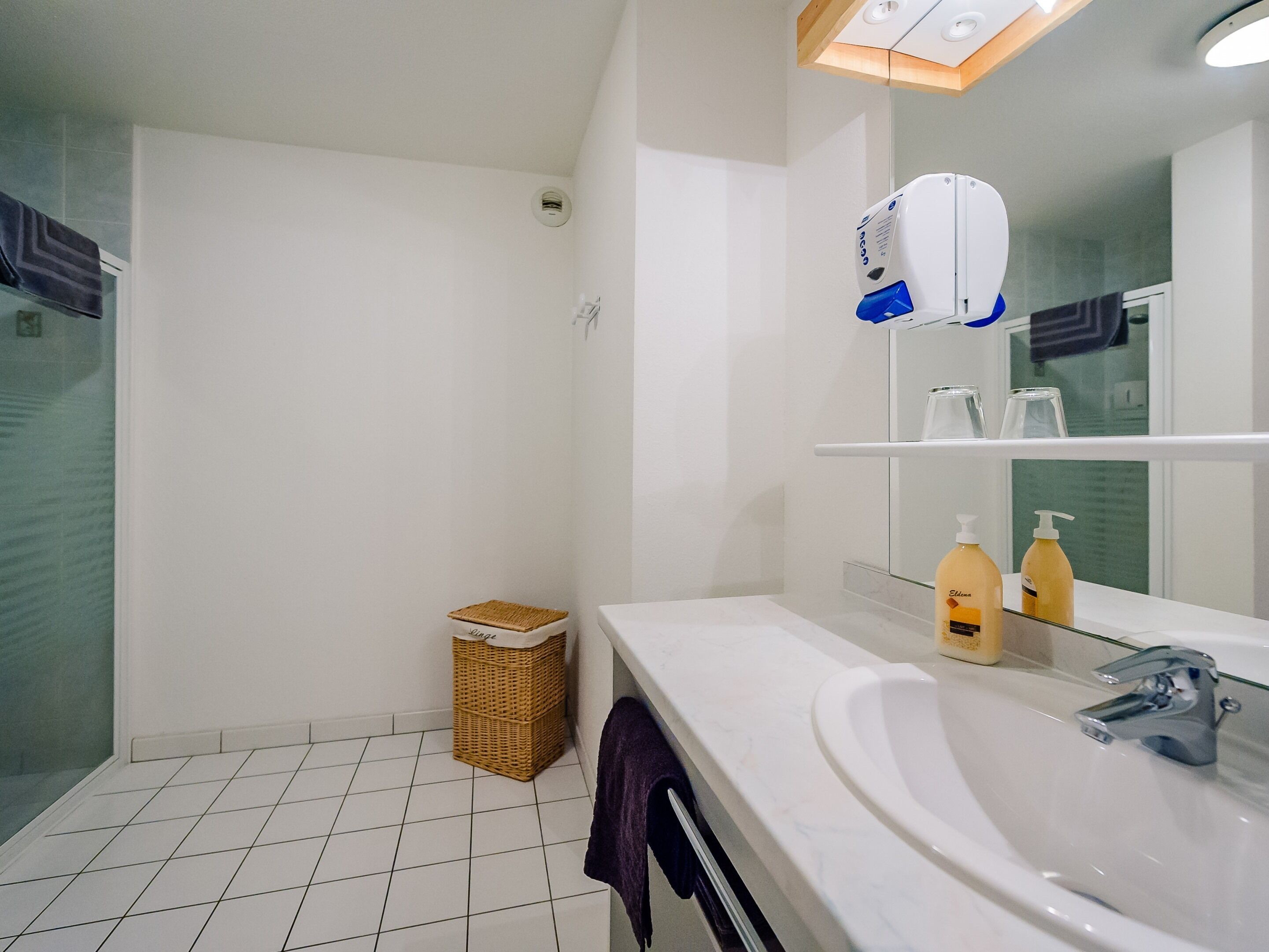 A bathroom with a white sink, a mirror, a hairdryer, and a small wicker basket.