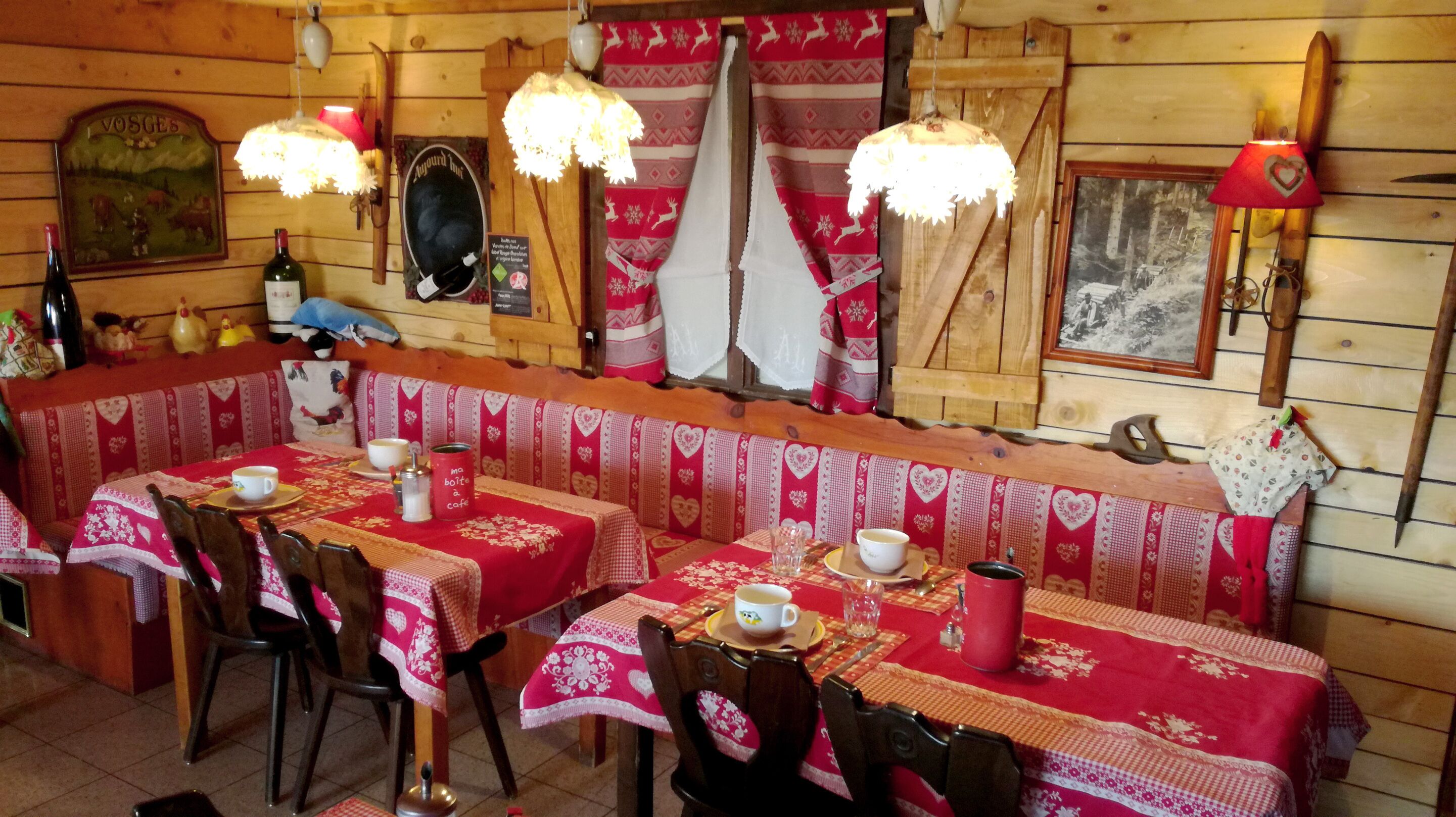 Un restaurant chaleureux avec des murs en bois, des nappes à motifs rouges et blancs et une décoration traditionnelle.