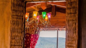 Ein Holzinnenraum mit Fenster, Vorhängen und einer Chandelier.