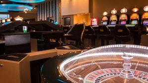 A casino with slot machines, a roulette table, and a piano.
