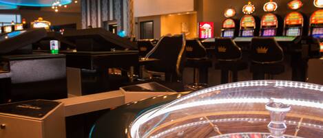 Un casino con máquinas tragamonedas, una ruleta y un piano.