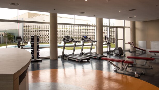 A gym with treadmills, weight machines, and a large window offering a view of the outdoors.