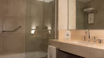 A modern bathroom with a glass-enclosed shower, a bathtub, and a vanity with a sink and mirror.