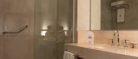 A modern bathroom with a glass-enclosed shower, a bathtub, and a vanity with a sink and mirror.