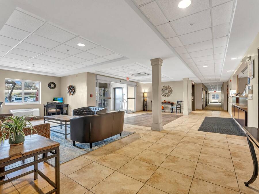 A spacious lobby with a seating area, a reception desk, and a view of the parking lot.