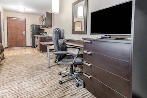 A hotel room with a desk, chair, TV, minibar, and a door leading to a bathroom. - Suburban Studios Washington, PA (Washington)