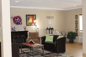 A lobby with a fireplace, seating area, coffee station, and decorative wall art. - Suburban Studios Washington, PA (Washington)