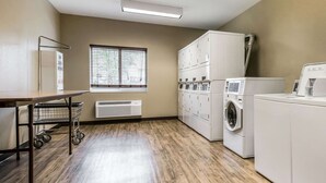 A laundry room with a large window, a cart, and stacked cabinets. - Suburban Studios Washington, PA (Washington)