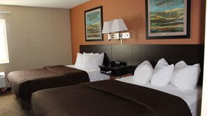 A hotel room with two beds, a nightstand, and two paintings on the wall. - Suburban Studios Washington, PA (Washington)