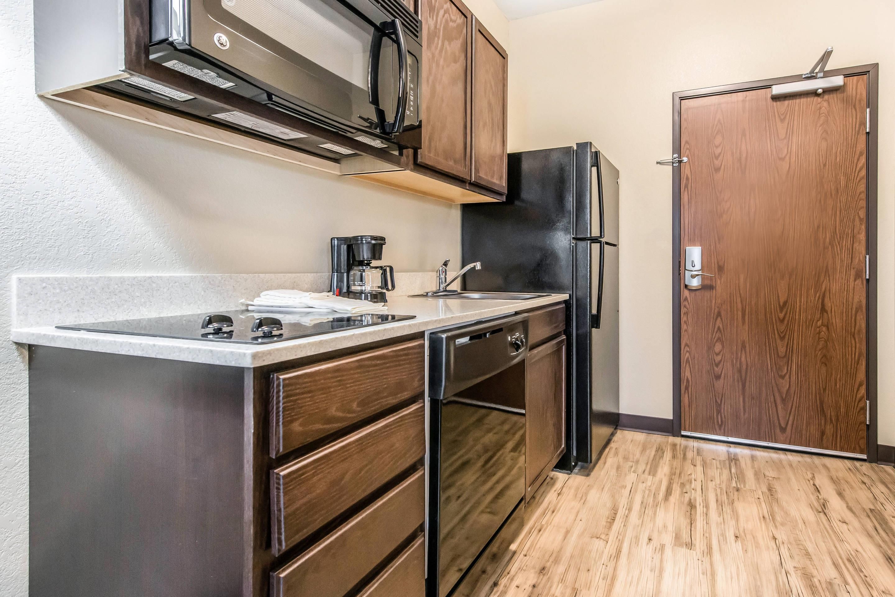A compact kitchen with a microwave, coffee maker, sink, and a refrigerator.