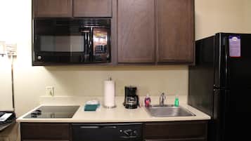 A kitchen with a microwave, coffee maker, and refrigerator.