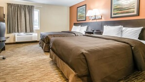 A hotel room with two beds, a desk, a chair, a lamp, and a painting on the wall.