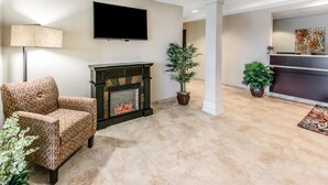 A lobby with a fireplace, a television, and a reception desk.