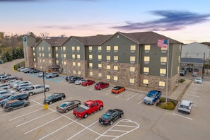 A multi-story hotel with a parking lot filled with various vehicles. - Suburban Studios Washington, PA (Washington)
