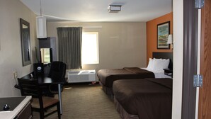 A hotel room with a desk, two beds, a window with curtains, a painting on the wall, and an air conditioning unit. - Suburban Studios Washington, PA (Washington)